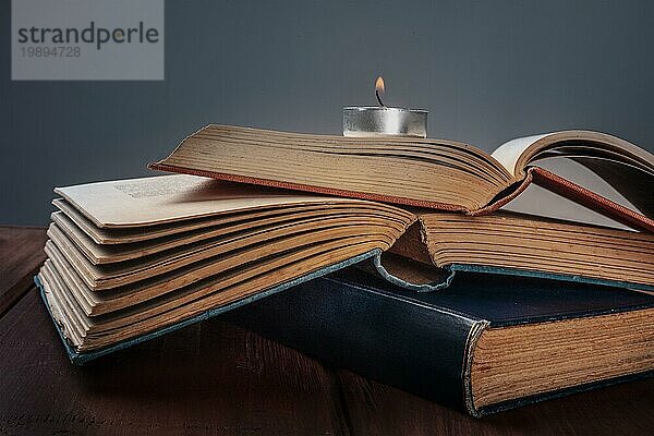 Ein Stapel alter Bücher mit einer brennenden Kerze und einem Platz für Text  selektiver Fokus