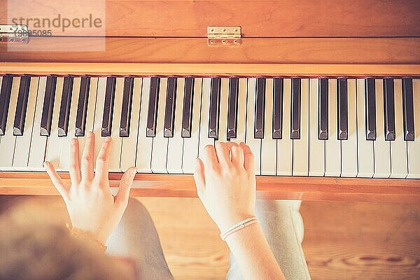 Junges Mädchen übt zu Hause am Klavier. Ausschnitt von Klavier und Händen