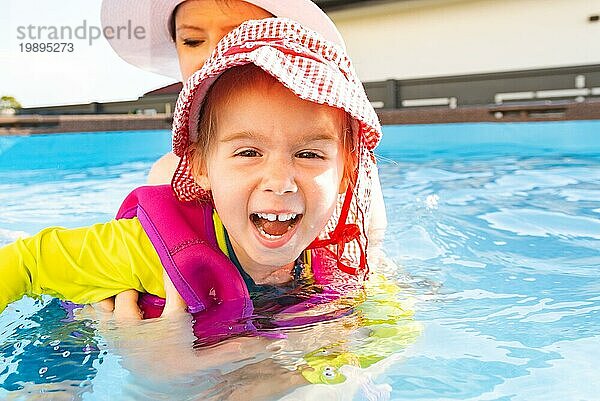 23 Jahre altes Kind mit Mutter im Schwimmbad lernen zu schwimmen. Baby im Schwimmen Westen und roten Hut.Sommer zu Hause Konzept