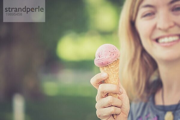 Lächelndes Mädchen genießt ihr Erdbeereis an einem Sommertag