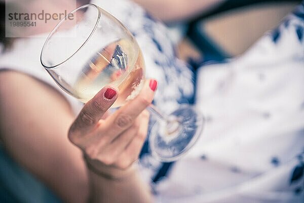 Schönes junges Mädchen mit blondem Haar hält ein Glas Wein und lächelt  Ferien