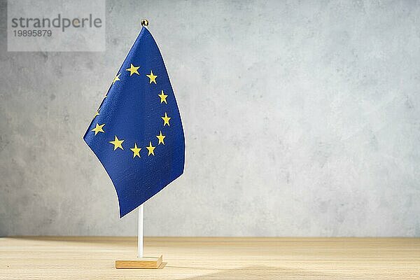 Tischflagge der Europäischen Union auf weißer  strukturierter Wand. Kopierraum für Text  Entwürfe oder Zeichnungen