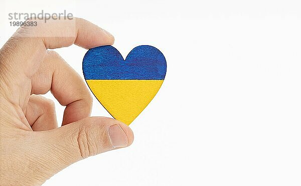 Hand hält eine Flagge der Ukraine auf Herzform. Weißer Hintergrund. Kopieren Raum