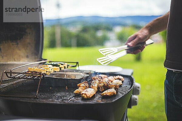 Nahaufnahme von Hähnchenflügeln  Käse und Gemüse auf dem Gasgrill. Sommerzeit  im Freien