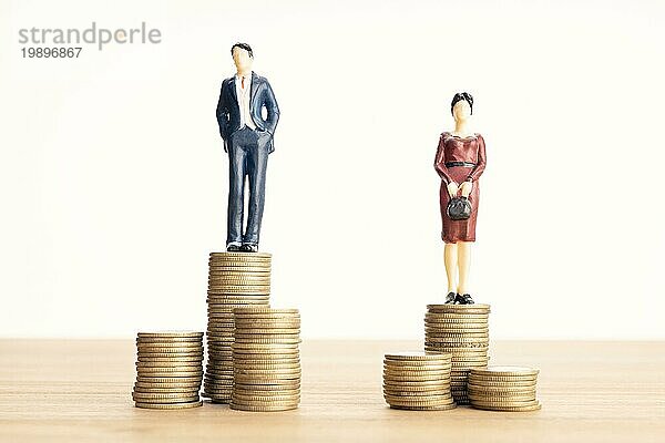 Lohnunterschied zwischen Männern und Frauen Konzept. Mann und Frau stehen oben auf dem Münzhaufen