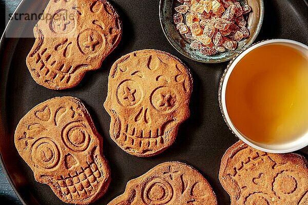 Halloween Ingwer Kekse in Form von Totenköpfen  Nahaufnahme  hausgemachte Dia de los muertos Kekse  Aufsicht auf einen dunklen Holzhintergrund