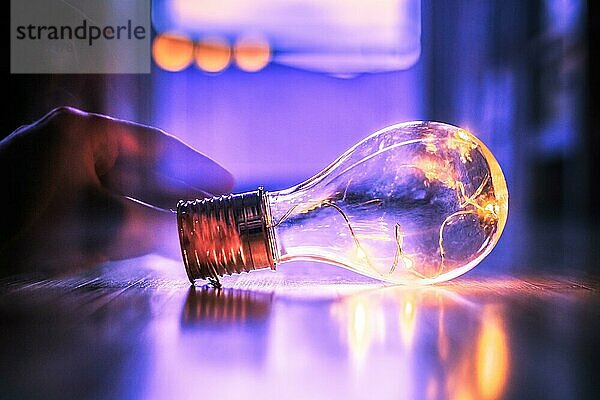 Die Hände halten eine LEDglühbirne über dem Holzboden. Symbol für Ideen und Innovation. Fenster und Licht im unscharfen Hintergrund