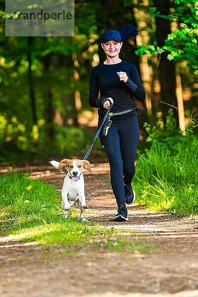 Mädchen läuft mit einem Hund (Beagle) an der Leine im Frühling  sonniger Tag im Wald. Kopieren Raum in der Natur