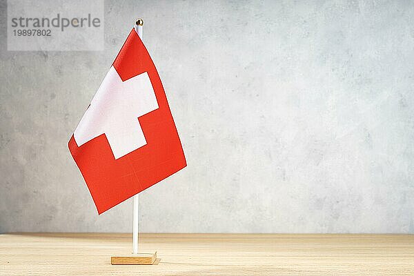 Tischflagge Schweiz auf weißer Strukturwand. Kopierraum für Text  Entwürfe oder Zeichnungen