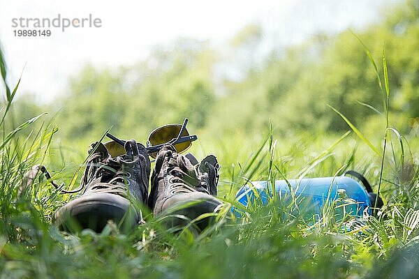 Schuhe und eine Flasche Wasser auf der grünen Wiese. Freie Zeit im Sommer