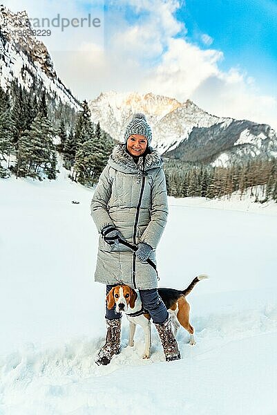 Junges Mädchen auf einem Spaziergang mit ihrem Beagle Hund im Winter mit Spaß auf Schnee zum ersten Mal