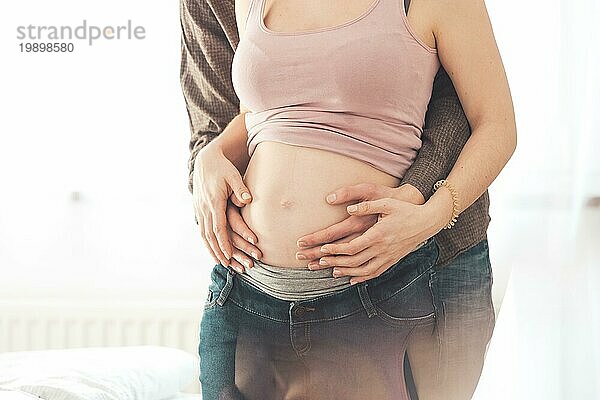 Nahaufnahme einer schwangeren Mutter und eines Vaters  die den Bauch umarmen  Kaukasier