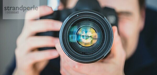 Der Fotograf steht hinter einer professionellen Kamera mit Teleobjektiv auf einem Stativ