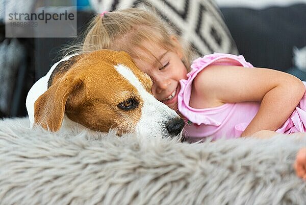 Kind kuschelt mit einem Hund auf dem Sofa im Hinterhof. Glückliche Kindheit mit Beagle Haustier