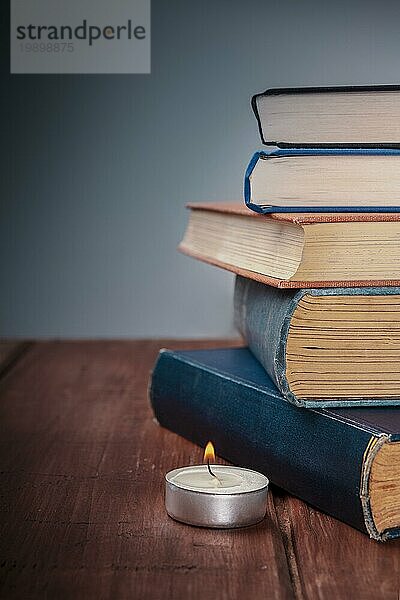 TA Stapel alter Bücher mit einer brennenden Kerze und Kopierraum  selektiver Fokus
