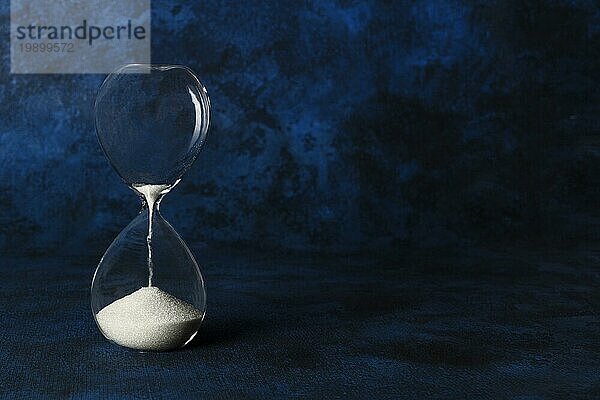 Die Zeit läuft ab Konzept. Eine Sanduhr mit Sand fallen durch  auf einem dunkelblauen Hintergrund mit Kopie Raum
