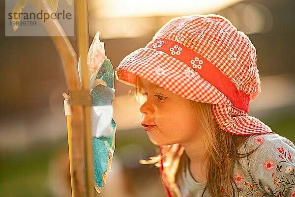Kleines Mädchen bläst in Windmühle Spielzeug auf sonnigen Sommer Sonnenuntergang. Entwicklungskonzept