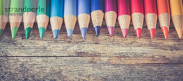 Satz mehrfarbiger Bleistifte auf einem rustikalen Holztisch  Kopierraum