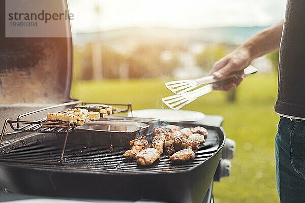 Nahaufnahme von Hähnchenflügeln  Käse und Gemüse auf dem Gasgrill. Sommerzeit  im Freien