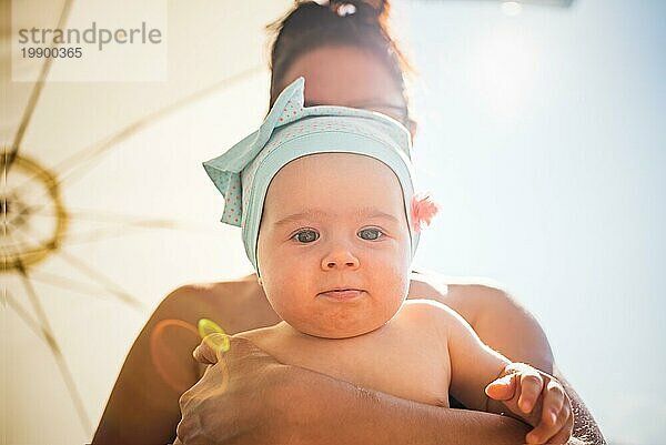 Mutter hält Baby gegen Himmel und Sonne im Hintergrund. Familie Konzept