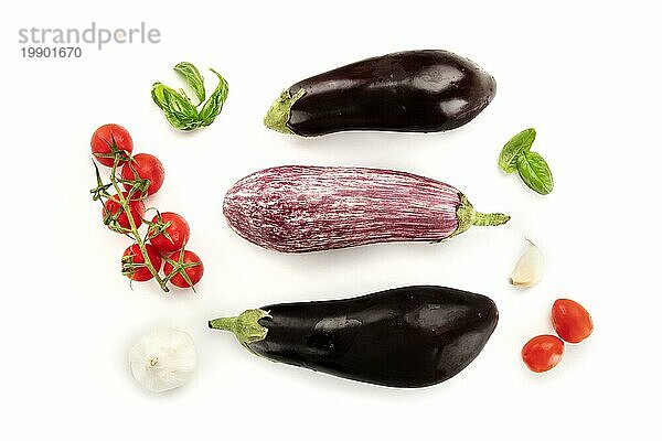 Eine Flachbildkomposition mit Gemüse. Auberginen  Tomaten  Basilikumblätter und Knoblauch  von oben auf einem weißen Hintergrund aufgenommen