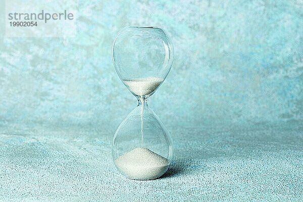 Die Zeit läuft aus Konzept. Eine Sanduhr mit Sand fallen durch  auf einem teal blaün Hintergrund mit Kopie Raum