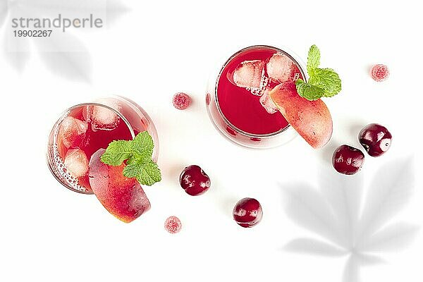 Leuchtend rote Mocktails mit frischen Früchten und organischen Schatten  von oben auf weißem Hintergrund mit Platz für Text aufgenommen