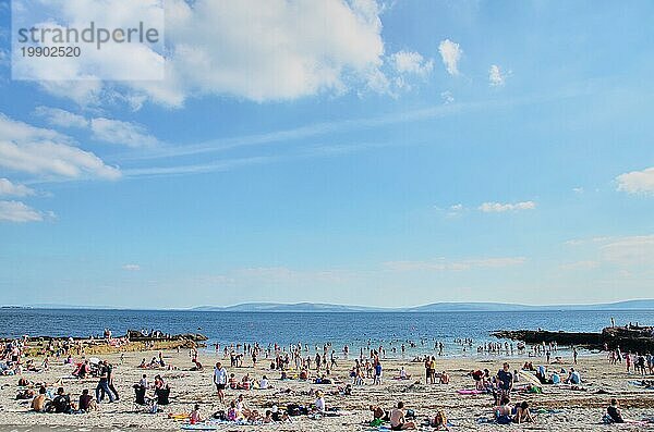 Galway  Irland  09.08.2012: Blick auf einen Strand voller Menschen an einem sonnigen Sommertag. Blaür Himmel mit ein paar Wolken und ruhiges Meer. Touristischer Ort  sehenswerter Ort  Europa