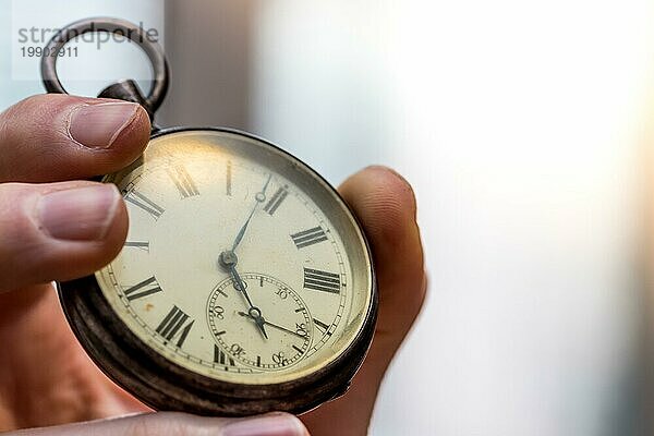 Die Zeit vergeht: Mann hält eine alte Uhr in der Hand  geschäftlicher Kontext  Kopierraum
