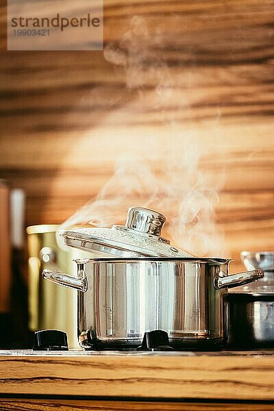 Dampfender Metalltopf in der Küche  Holz