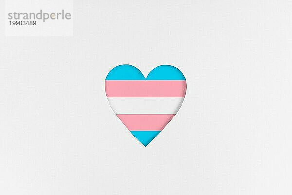 Transgender Flagge auf Herzform vor weißem Hintergrundem Karton Hintergrund. Bedruckter Karton mit ausgestanzter Herzform. Ansicht von oben