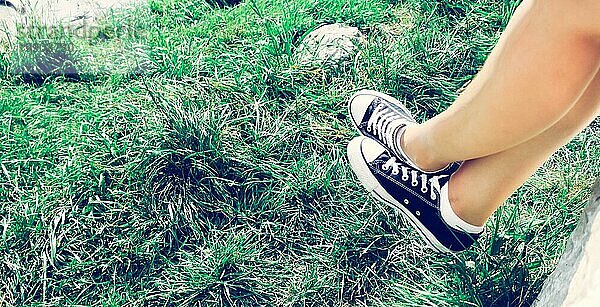 Schwarze Turnschuhe und grünes Gras im Sommer: freie Zeit für Teenager