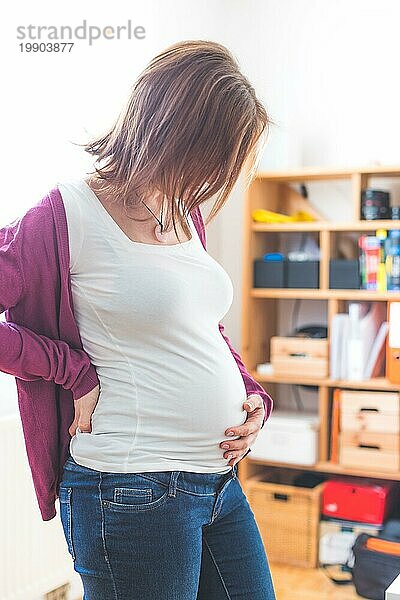 Nahaufnahme eines schwangeren Bauches  kaukasische Mutter mit weißem Hemd und magentafarbener Jacke