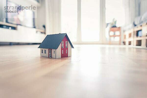 Rotes Hausmodell auf dem Boden  drinnen. Konzept für neues Haus  Grundstück und Anwesen