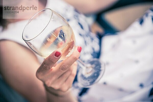 Schönes junges Mädchen mit blondem Haar hält ein Glas Wein und lächelt  Ferien