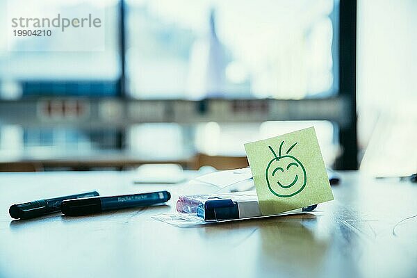 Smiley Illustration am Arbeitsplatz  Werkstatt. Stifte und Fenster im unscharfen Hintergrund