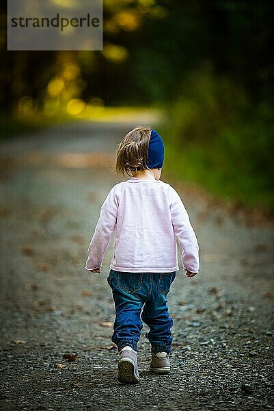 Porträt eines 2 Jahre alten Mädchens im Wald  das alleine spazieren geht. Möchte den Eltern nicht folgen. Konzept der Unabhängigkeit des Kindes