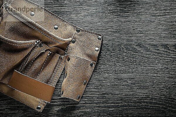 Werkzeuggürtel aus Leder auf Holzbrett