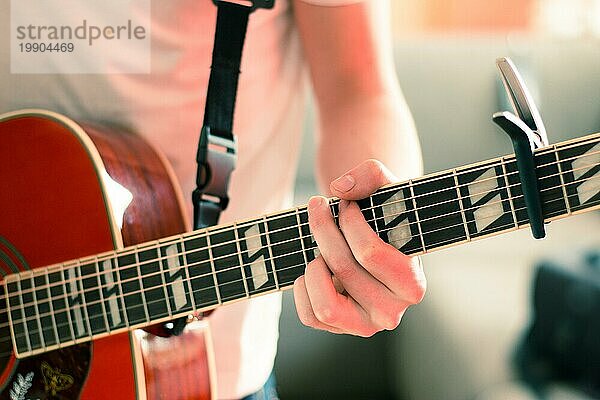 Junger Mann spielt eine Sunburst Westerngitarre: Ausschnitt  unscharf