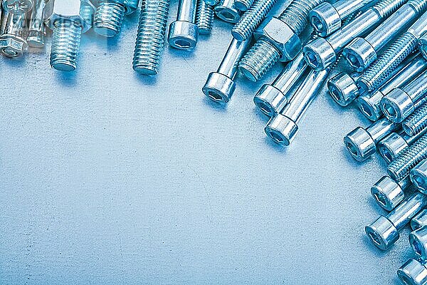 Heap of metal threaded hexagon bolts on metallic background repairing concept