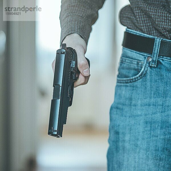Ein Undercover Polizist hält eine schwarze Waffe in der Hand  bereit zum Schießen
