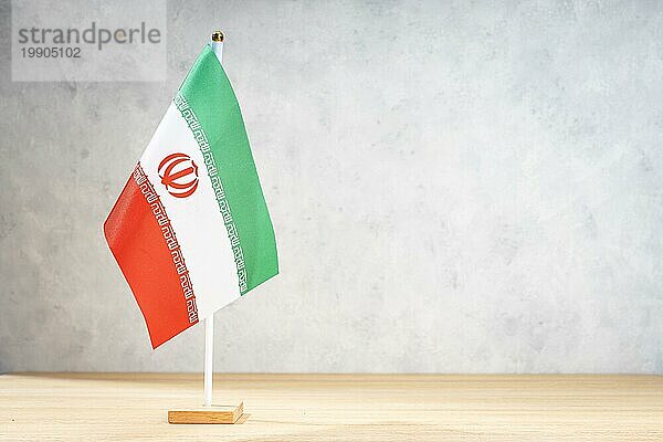 Iranische Tischflagge auf weißer  strukturierter Wand. Kopierraum für Text  Entwürfe oder Zeichnungen