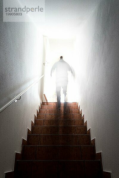 Ein Mann geht eine Kellertreppe mit Geländer hinauf. Natürliches helles Sonnenlicht
