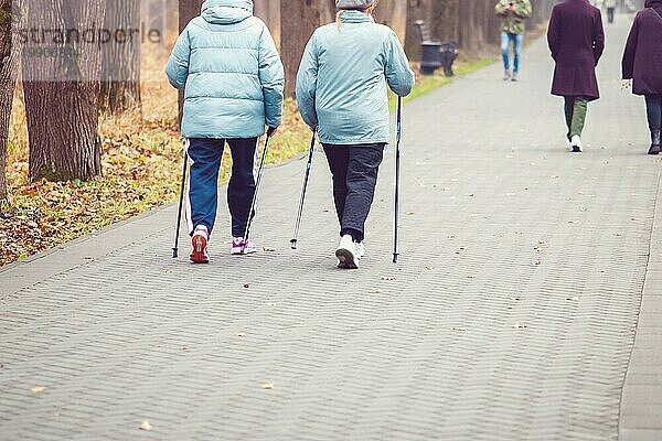 Spaziergang mit Stöcken im Herbst  ältere Frauen trainieren im öffentlichen Park