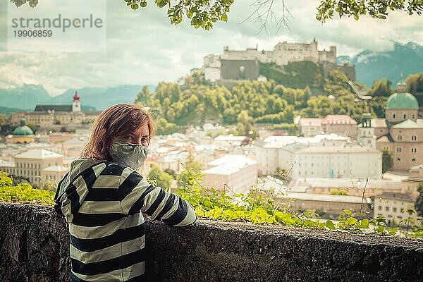 Weibliche Touristin mit Gesichtsmaske genießt den Blick über die Altstadt von Salzburg