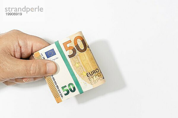 Eine Hand hält eine gefaltete Euro Banknote auf weißem Hintergrund. Leerzeichen kopieren