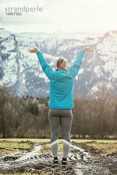 Mädchen in blaür und grauer Sportkleidung steht auf einem Feld und macht eine wunderbare Geste