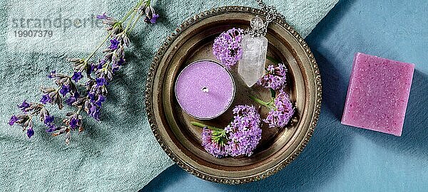 Aromatherapie Panorama. Duftkerze  Seife und Parfümfläschchen  Aufnahme von oben mit Eisenkraut und Lavendelblüten auf blauem Hintergrund