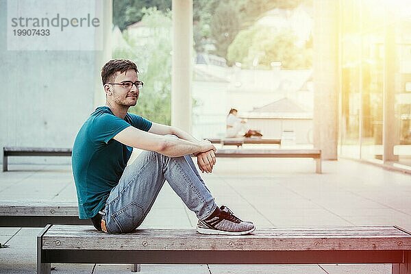 Männlicher junger Angestellter sitzt im Freien und macht eine Pause. Städtische Geschäftsumgebung