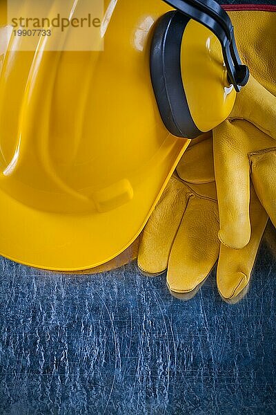 Arbeitshelm Sicherheit Ohrenschützer und gelbe Schutzhandschuhe auf zerkratzt metallischen Hintergrund Konstruktion Konzept
